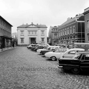 Markt: rechts vorne parkende Pkws, dahinter das Stadthaus, links die Kreissparkasse Stormarn, mittig im Hintergrund das Rathaus: Blick von Süden