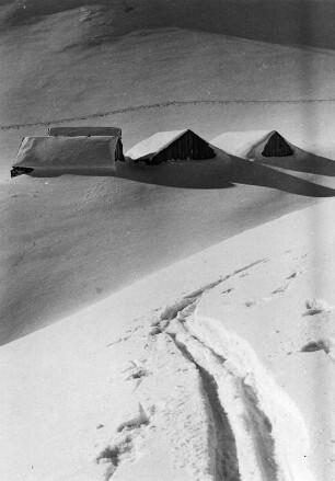 Winterbilder. Hütten im tiefen Schnee. Im Vordergrund Skispuren