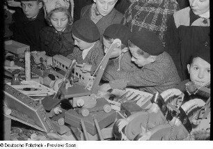 Kinder an einem Stand mit Holzspielzeug auf dem Weihnachtsmarkt