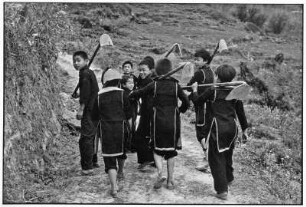 Kinder in traditioneller Kleidung mit Hacken in der Bergwelt von Sa Pa