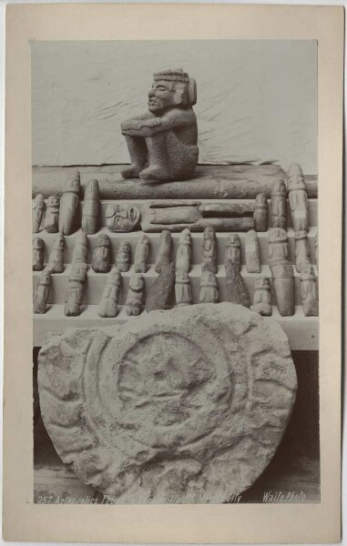 Several objects: Crouching stone figure ("sad indian"), reclining female stone figure, several small stone idols and fragment of a relief.