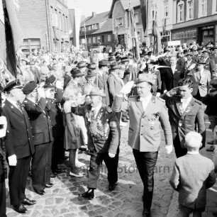 Schützenfest: Veranstalter Schützenverein Reinfeld und Umgebung von 1954 e.V.: Umzug: Paul-von-Schoenaich-Straße, Höhe Rathaus: Schützenkönig Otto Maaß, Vorsitzender Hans-Georg Talies und Jungschützenkönig Axel Holz schreiten Front der mit Fahne angetretenen Schützen ab: hinten rechts Bürgermeister Richard Hingst, Schützen: hinten links Zuschauer, 8. September 1963