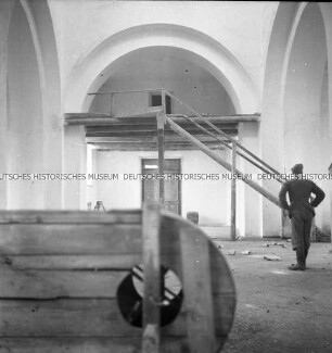 Ausgeräumter Innenraum einer russisch-orthodoxen Kirche mit improvisierter Getreidemühle und deutschem Soldat