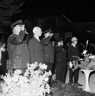 Haarmann, Wennemar: Verabschiedung: Rolfshagener Kupfermühle: Großer Zapfenstreich der Kreisfeuerwehr: Wennemar Haarmann steht auf einem Podest, um ihn herum salutierende Feuerwehrleute, dahinter Gäste
