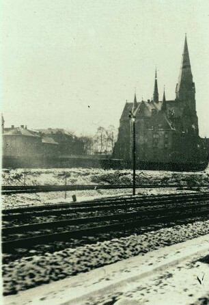 Kirche im Winter mit Eisenbahngeleisen im Vordergrund