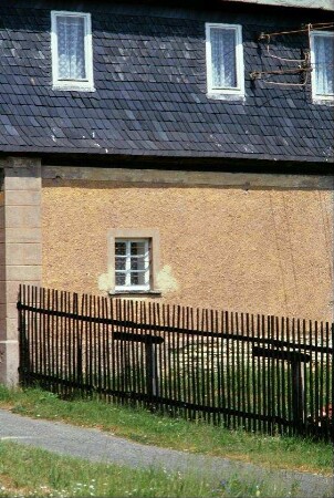Fassadendetail: OG verschiefert, Fenster im EG mit Gitterstäben, Gartenzaun
