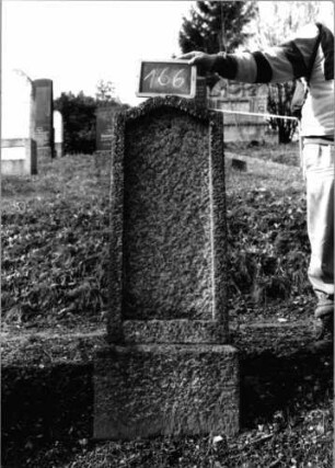 Grabstein 166 (Index: 100090475) Material: Granit Zustand: gut, Schriftplatte fehlt Maße HxBxT: 145x45x22 cm Beschreibung: konische Stele, Sockel, Konvexbogenabschluß, Schriftfeld eingetieft: Grabstein 166 (1)