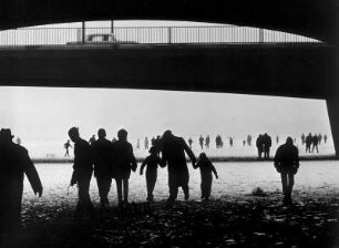 Hamburg im Winter. Unter der Neuen Lombardsbrücke (seit 1963 Kennedybrücke). Menschen laufen auf der zugefrorenen Alster