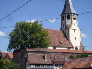 Ansicht von Süden mit Kirche (Chorturm mit Schlitzfenstern im Mittelgeschoß sowie achteckiger Glockenstube) über Kirchhofmauer sowie umgebenden Ortshäusern