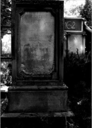 Grabstein 162 (Index: 100109743) Material: Sandstein, weiße Marmorplatte Zustand: Sockel leicht verwittert Maße HxBxT: 156x60x34 cm Beschreibung: rechteckige Stele, getreppter Sockel, Schriftplatte mit eingezogenen Ecken: Grabstein 162