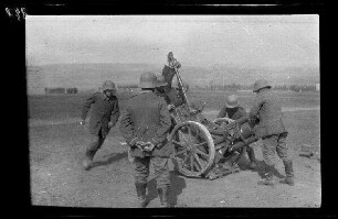 Übungsgelände II bei Mouzon (Dep. Ardennes, Frankreich): 6 Soldaten mit Stahlhelm auf einem Feld beim Abladen eines auf einem Wagenkarren montierten [Minenwerfer]