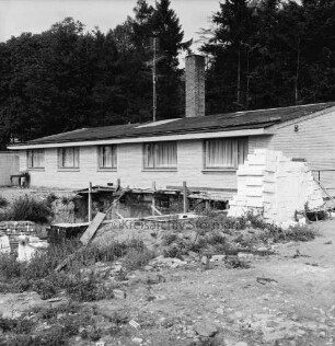 Gutsgärtnereigelände: Bungalow: davor Baugrube mit Grundmauer: rechts Ziegelstapel: hinten Bäume