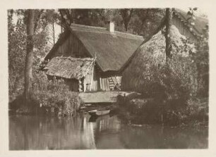 Mark Brandenburg. Leipe. Ansicht eines typischen wendischen (sorbischen) Bauernhofes in Blockbauweise und mit Reetdach. Dafur ein Heuschober. Am Bootsanleger liegt ein Spreewaldkahn im Wasser