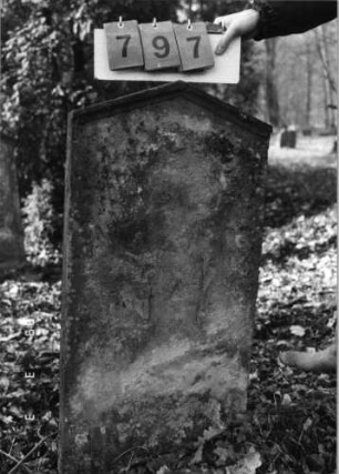 Grabstein 797 (Index: 99751523) Material: Sandstein Zustand: abgeblättert mit völl. Textverlust Maße HxBxT: 99x49x11 cm Beschreibung: Stele, giebelartiger Abschluß mit Verdachung: Grabstein 797