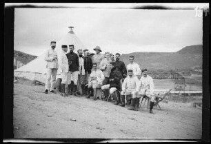 [San Juan de las Minas (Provinz Nador, Marokko):] Gruppenbild mit Offizieren des Infanterie-Regiments Mallorca in hellgestreiften Uniformhosen, hellen und dunklen Uniformjacken und überwiegend niedrigen, runden Feldmützen (Offizier in der Mitte mit Tropenhelm) vor einem Zelt