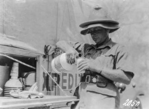 Afrika. Expeditionsmitglied an einem Expeditionswagen mit einer Wasserflasche. Werbung für Katadyn-Produkte, 1931