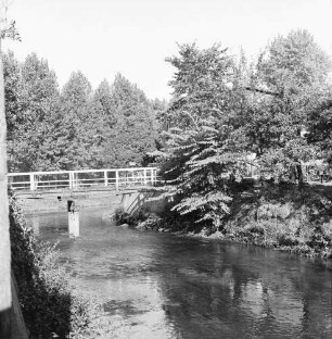 Trave: hinten links Fußgängerbrücke: dahinter Baumreihe am Ufer: rechts Alter Friedhof