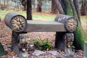 Steinbank mit verzierten Seitenlehnen auf dem Kirchhof