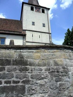 Kirchturm von Süden (mit Schießscharten im Mittelgeschoß) über Kirchhofmauer (mit Werksteinen im Mauersteinverband)