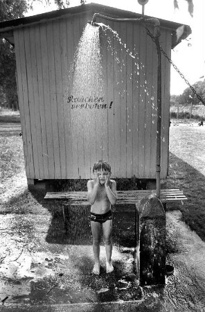 Kind unter der Dusche an einem Bauwagen