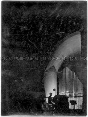 Organist am Orgeltisch in einer dunklen Kirche