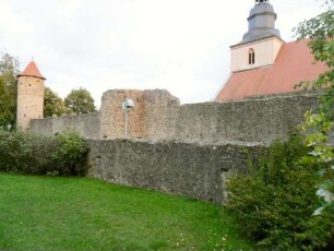 Nordflanke von Nordwesten mit Kirchhofmauer und Nordturm (flankierender Halbschalenturm)- einstiger Wehrgang in erhöhter Schußposition über Zwinger-sowie Zwingermauer (mit Büchsenscharten)