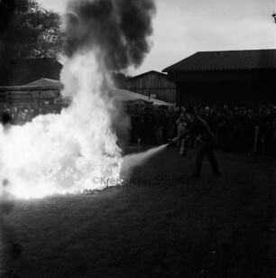 Freiwillige Feuerwehren Westerau, Trenthorst und Ahrensfelde: Feuerwehrübung "Waldbrand": Dorfteich: Löschen eines Benzinbrandes mit Handfeuerlöscher: rechts Feuerwehrmann: links Feuer: im Hintergrund Zuschauer und Häuser
