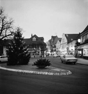 Besttorstraße Ecke Bahnhofstraße: Tannenbaum mit Adventsbeleuchtung auf der Verkehrsinsel, rechts die Besttorbrücke mit parkenden Pkws und Gebäuden mit Adventsbelechtung, Blick Richtung Norden