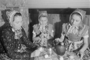 Schleifer Frauen und Mädchen in Schleifer Tracht beim Verzieren von Ostereiern. : Holcy a žony w Slepjanskej drasće při debjenju jutrownych jejkow pola Wěrikec w Rownom.