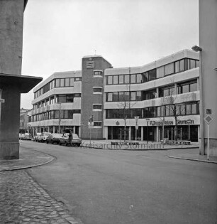 Kreissparkasse Stormarn: Hagenstraße: Zentrale: vor Einweihung, mit Firmenname: im selben Gebäude links Buchhandlung Spethmann: davor parkende Autos, Mann: Vorplatz mit jungen Bäumen, runden Sitzbänken, Straßenschilder, Straßenlampen: links Eckhaus Altbau Kreissparkasse an Markt: rechts Historisches Rathaus