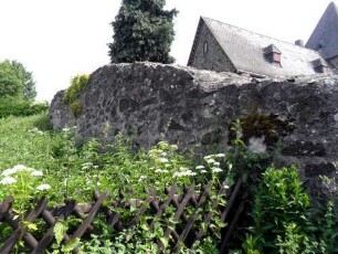Ansicht von Südwesten mit Kirchhofmauer (Wehrgang mit Steinbrüstung und Schießscharten abgetragen) über Feldseite (ehemals verlaufender Graben verfüllt)