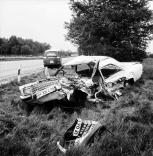 A 1: Verkehrsunfall: Zusammenstoß von Pkw und Lieferwagen: Wrack von Unfall-Pkw neben Straße, vorne Trümmerteil: dahinter auf Seitenstreifen Unfall-Lieferwagen: Leitpfosten: hinten Mittelstreifen, Autos auf Gegenfahrbahn: Büsche, Bäume