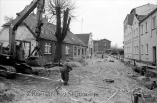 Bahnhofstraße: Baustelle mit Baugerät und Absperrungen: vorn Mitte Arbeiter, links Bagger: rechts und links Häuser: hinten Kreuzung mit Mewesstraße rechts, Ratzeburger Straße in der Mitte und Berliner Ring links