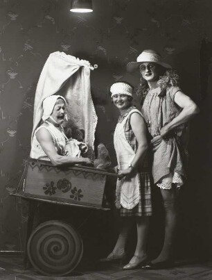 Zwei Männer als Mutter und Kind verkleidet. Hulda Hanisch als Kindermädchen mit Kinderwagen