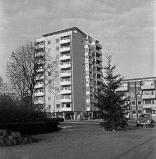 Kurparkallee: vorn Kurpark mit Bäumen und Sträuchern: rechts und links parkende Pkws: hinten links Hochhaus "Liebe", rechts daneben Wohnblock