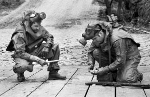 Zwei Soldaten mit Gasmasken legen eine Sprengladung an eine Brücke während des NATO-Manövers Flinker Igel, an dem 52.000 Soldaten aus verschiedenen NATO-Staaten teilnahmen, um nukleare und konventionelle Kampfsituationen zu simulieren, Bayern