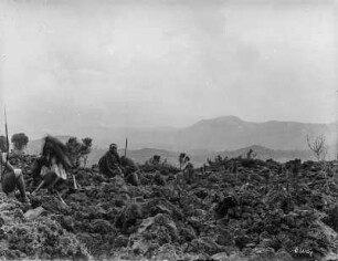 Berglandschaft : Aussicht von einer Anhöhe auf eine Berglandschaft, im Vordergrund sitzt eine Gruppe Männer.