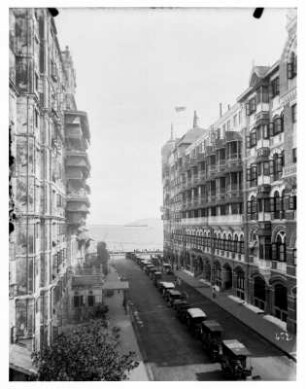 Bombay (Indien). Straßenflucht mit parkenden Automobilen und Taj-Mahal-Hotel. Blick zum Hochseepassagierdampfer "Cleveland"