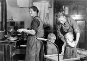 Arbeitsmaid des Reichsarbeitsdienstes bei der Kinderbetreuung in der Bauernküche