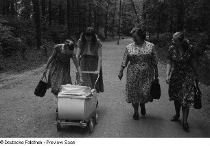 Renate Rössing (2.v.l.) mit einem Kinderwagen und drei Frauen, einen Parkweg entlanggehend