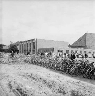Sachsenwaldschule Gymnasium Reinbek: Schulstraße: Erweiterungsbau: Einweihung: vorn Fahrräder auf unbefestigtem Schulgelände: dahinter Schüler: hinten links Turnhalle: hinten rechts Verbindungsbau: dahinter Altgebäude