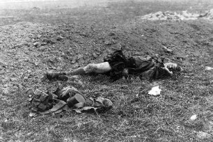 Toter Soldat mit zerrissenen Gliedmaßen; neben ihm liegt seine Ausrüstung