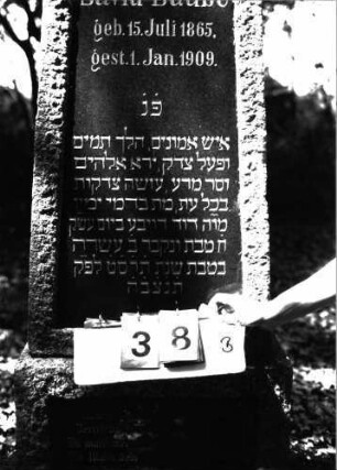 Grabstein 38 (Index: 100101207) Material: Granit, schwarze Glasplatte im Sockel Zustand: gut Maße HxBxT: 163x60x28 cm Beschreibung: Obelisk, Sockel, Schriftplatten Symbolik: Voluten: Grabstein 38B (Nachholaufnahme)