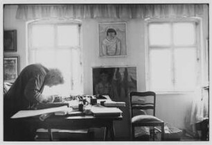 Die Malerin Charlotte E. Pauly in ihrer Wohnung, an der Wand mehrere Werke der Künstlerin