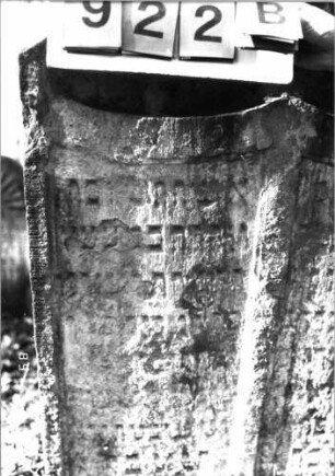 Grabstein 922 (Index: 99753200) Material: Sandstein Zustand: stark abgeblätt/verwitt/großer Textverl. Maße HxBxT: 120x84x11 cm Beschreibung: Doppelstele, zwei Schriftfelder Symbolik: Lilien, Schriftband: Grabstein 922B