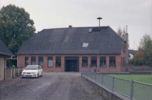 Schlamersdorf: Dorfstraße 23: traufständiges Backsteinhaus, mit Umbauten: Straßenfront mit Eingangstür: rechts Giebelseite, daran Außenschornstein: auf Dach Sirene: von vorne Einmündung Weg