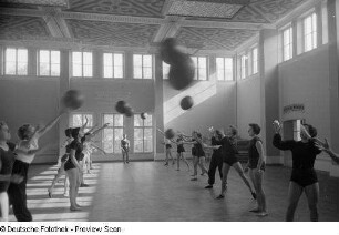Sportlerinnen während einer Übung mit einem Medizinball in einer Sporthalle der Deutschen Hochschule für Körperkultur in Leipzig