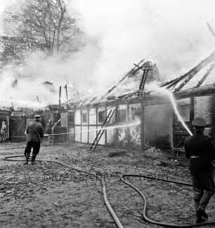 Schleushörn: Brand: Trabergestüt und Reitstall "Schleushörn" von Klaus Martens: brennender Stall mit Reetdach: darüber Rauchwolken: vorn rechts und hinten links Feuerwehrmänner beim Löschen