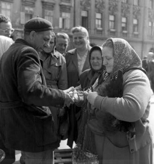 Verkauf eines Huhnes auf einem Markt umringt von Schaulustigen