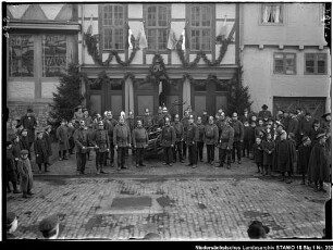 Übungen der Wolfenbütteler Freiwilligen Feuerwehr Enthält: Gruppe von Feuerwehrleuten vor einem geschmückten Fachwerkhaus mit dem Emblem "50", daneben Zuschauer